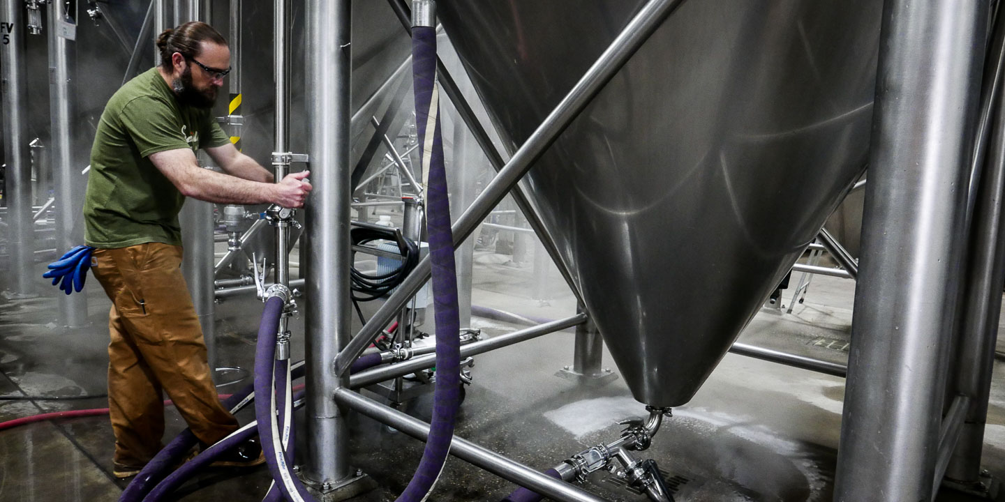 Brewer Lynden attaches a hose to a fermenting tank