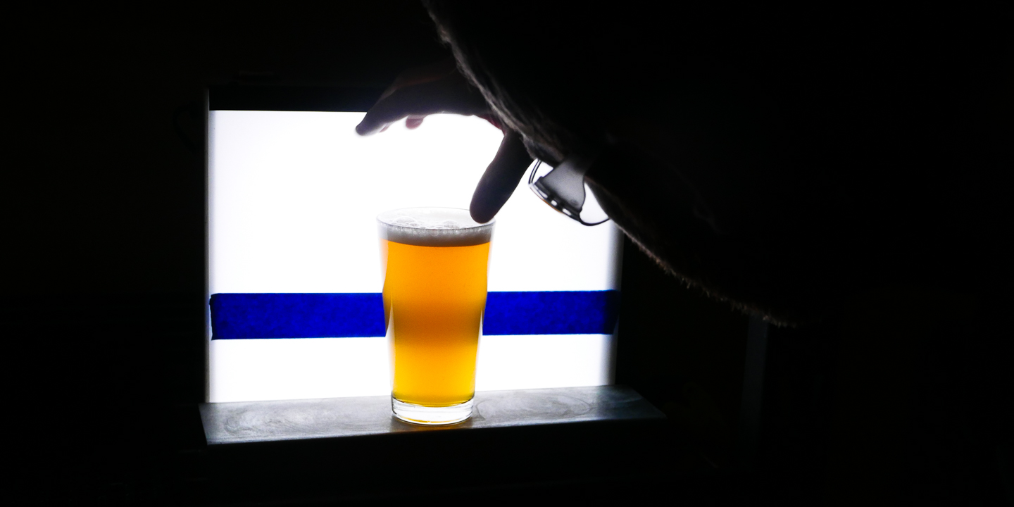 A glass of beer is put in front of a light box to test for clarity