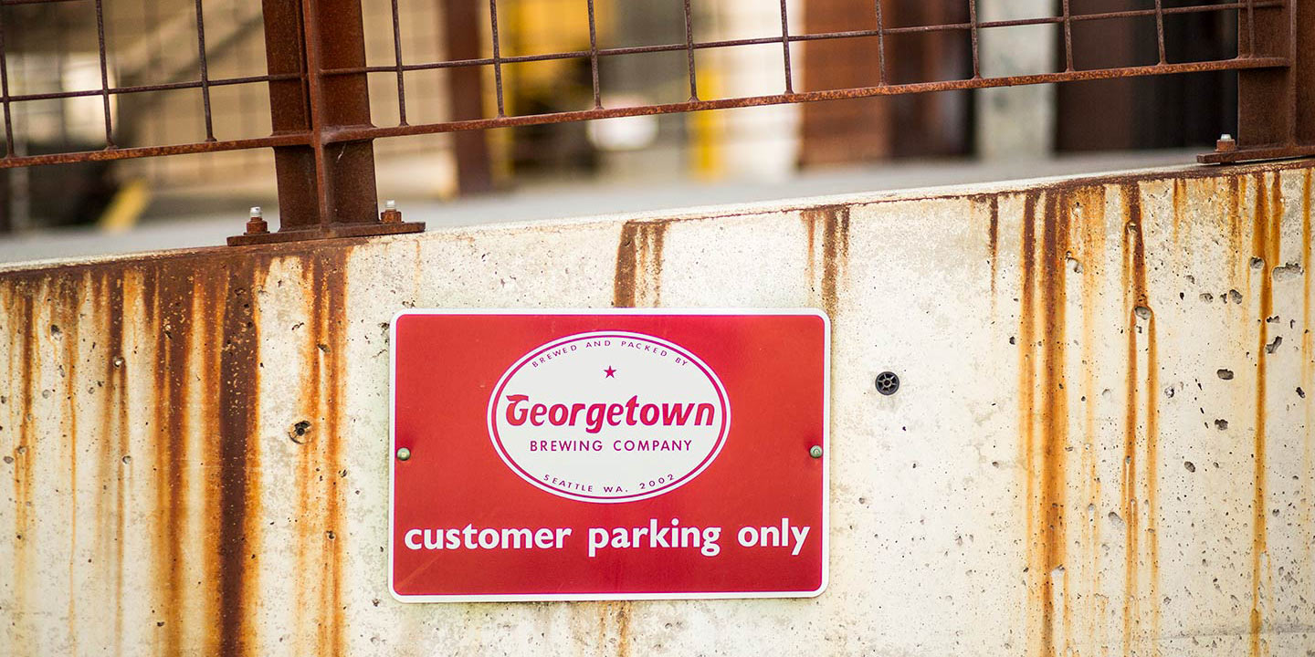 a customer parking sign attached to a low concrete wall