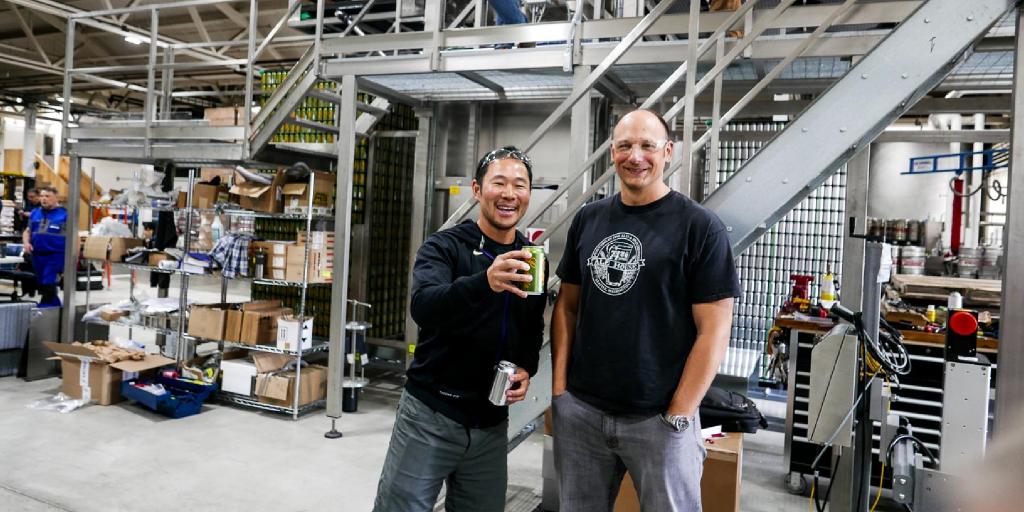 Manny and Roger toast using cans that just came off the canning machine